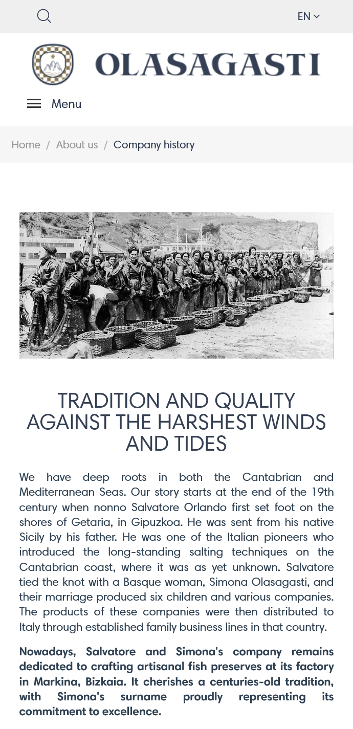 Sección nosotros (About us) en ingles de la versión móvil de la página web de Conservas Olasagasti, con una fotografía histórica de mujeres trabajando en la costa y cestas de pescado
